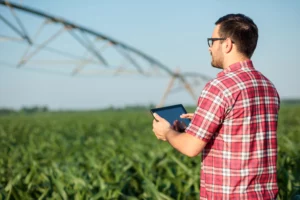 Imagem de destaque para artigo sobre agricultura 5.0 no Blog Assinei. Descrição da imagem: homem branco de óculos utiliza um tablet em uma propriedade rural (Créditos: Shutterstock)