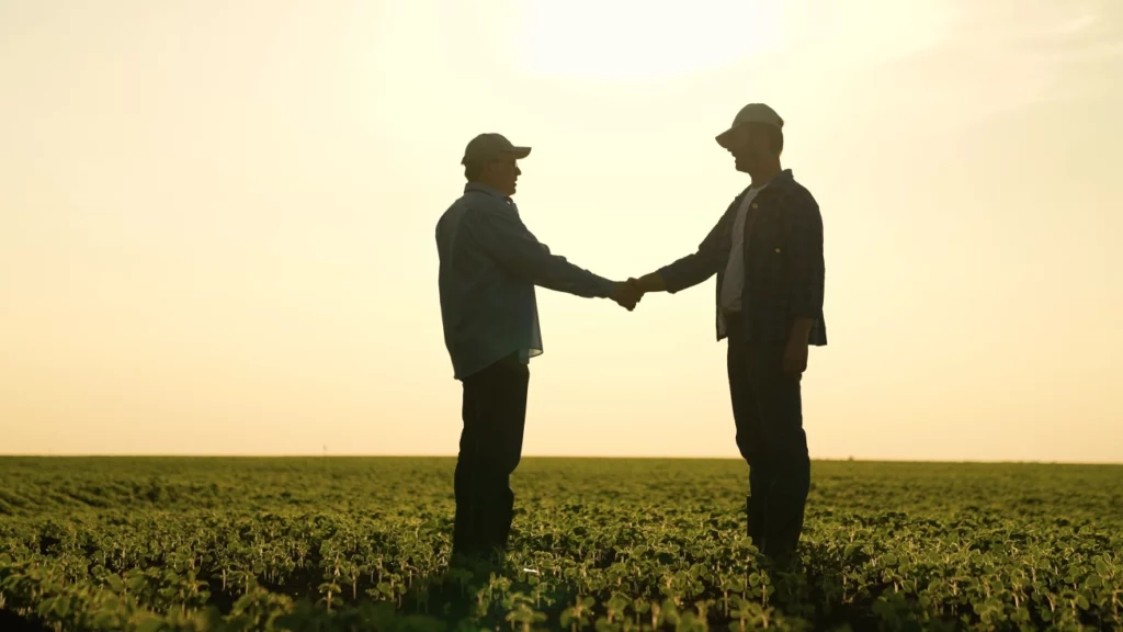 Imagem de destaque para artigo sobre duplicata rural no Blog Assinei | Descrição da imagem: dois homens dão um aperto de mãos em um campo agrícola | Créditos da imagem: Shutterstock